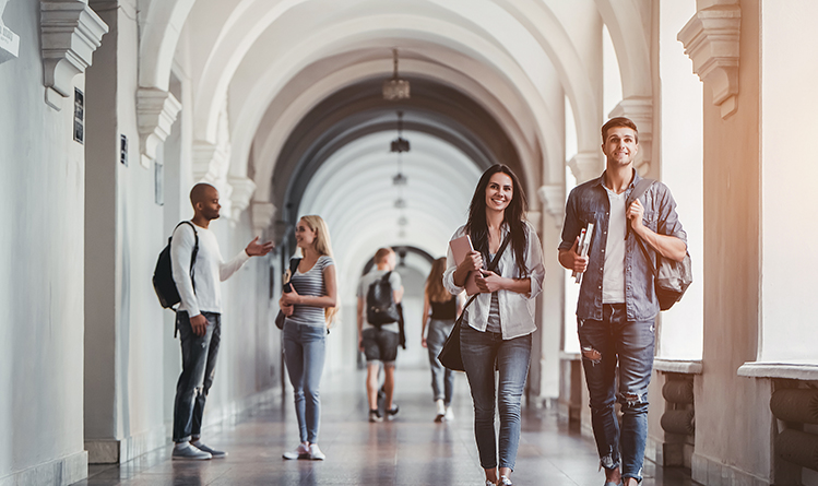 Six students with their bags, in a long hallway walk, talk and discuss, in pairs.