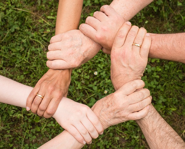 A top view shows six hands holding one another on the wrist, connecting a circle.